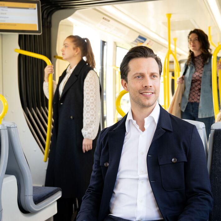 Passenger on tram, sitting on a two-seater.