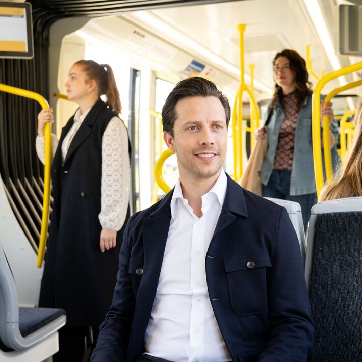 Reiziger in tram, zittend op een tweezits.