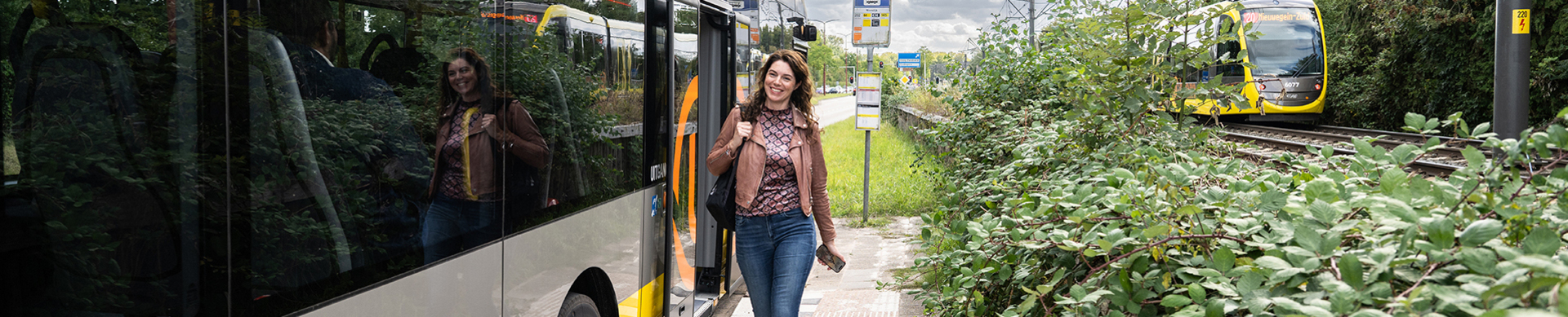 Image of woman at bus platform, with tram in the background