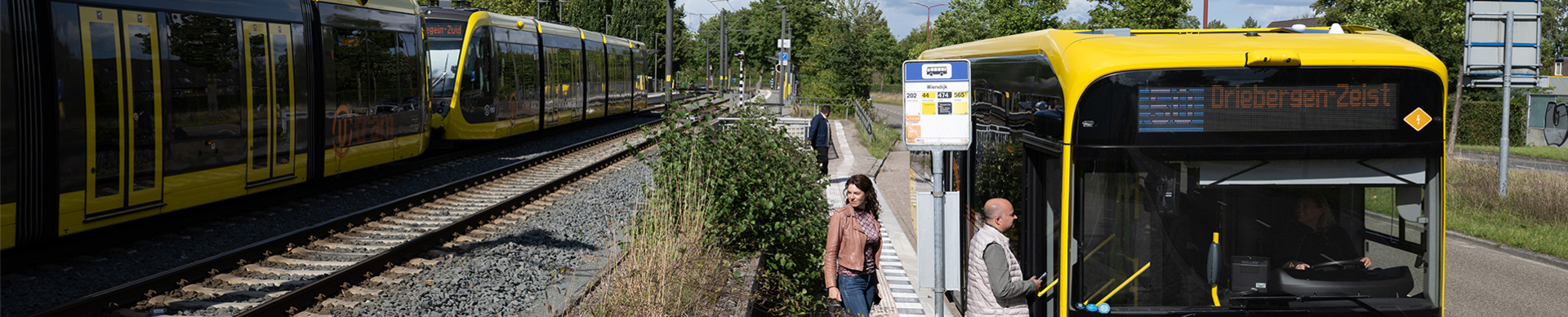 Afbeelding reizigers insappen in bus met daarnaast een langsrijdende tram