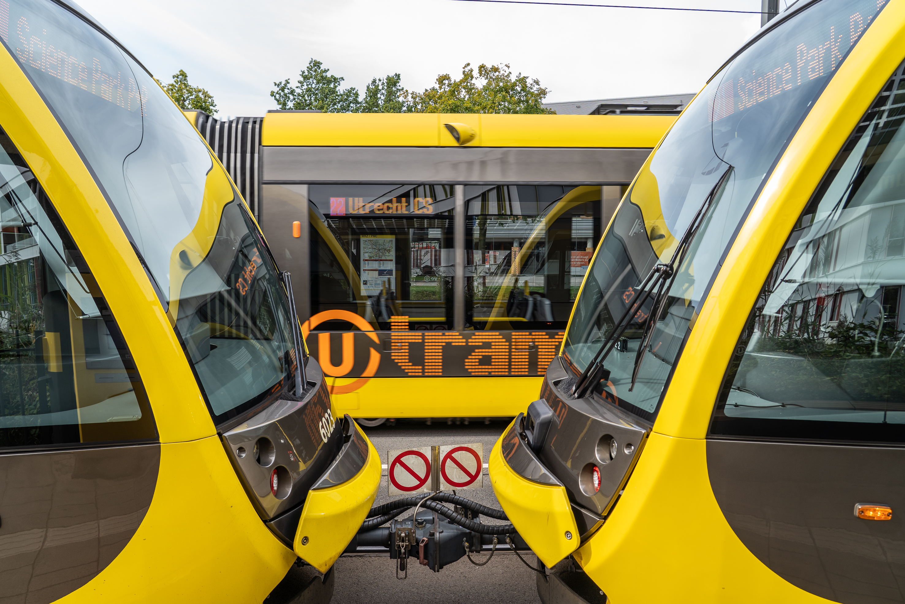 Yellow U-OV tram bound for Utrecht Central Station, photographed between two coupled trams at a tram depot in Utrecht.