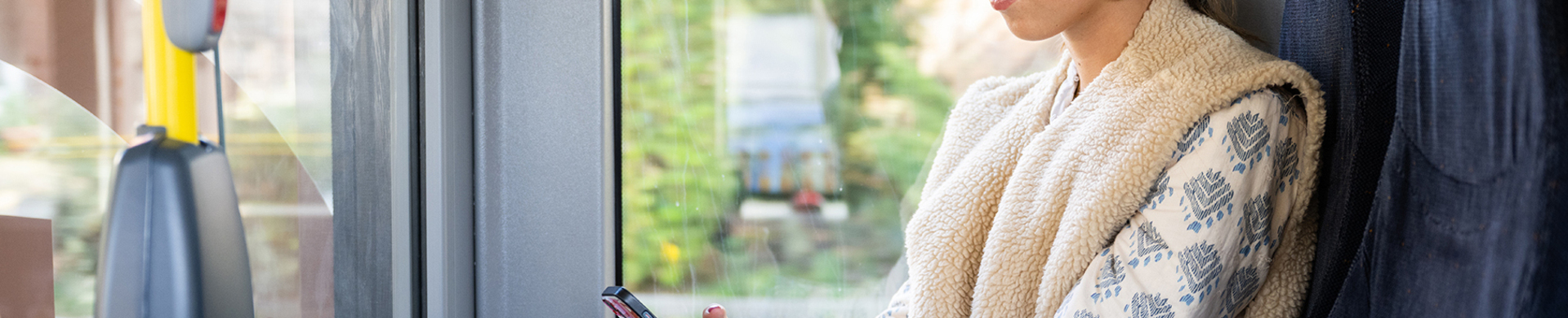 Afbeelding van jonge vrouw zittend in de bus en kijkt op haar mobiel