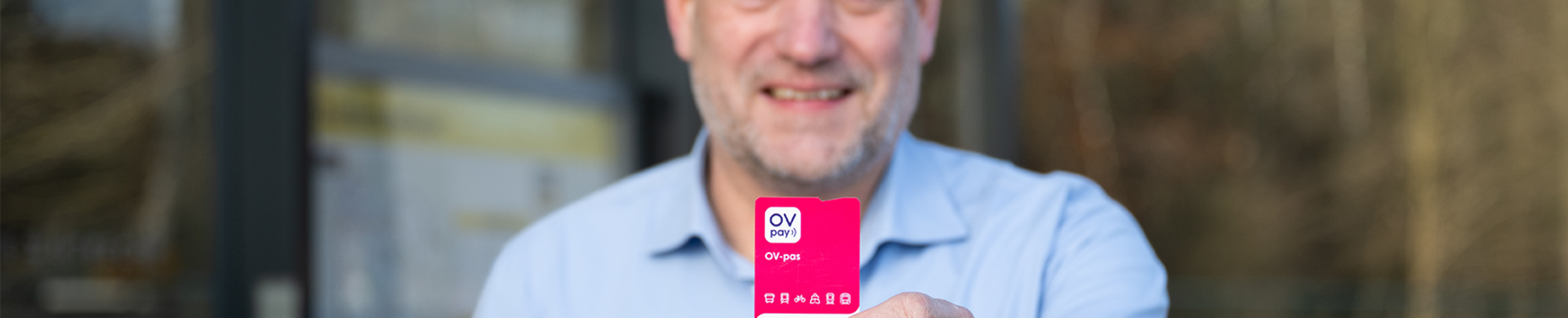 Man at a bus stop holding a public transport pass in his hands