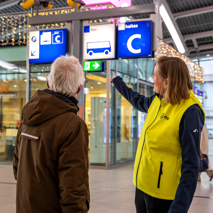 Travel information officer at the station assists a passenger.