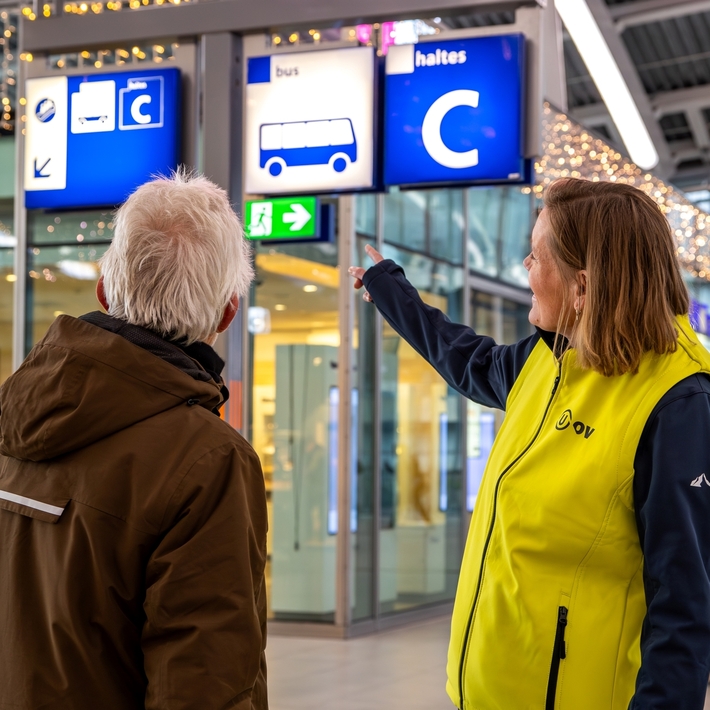 Reisinformant op het station helpt een reiziger.